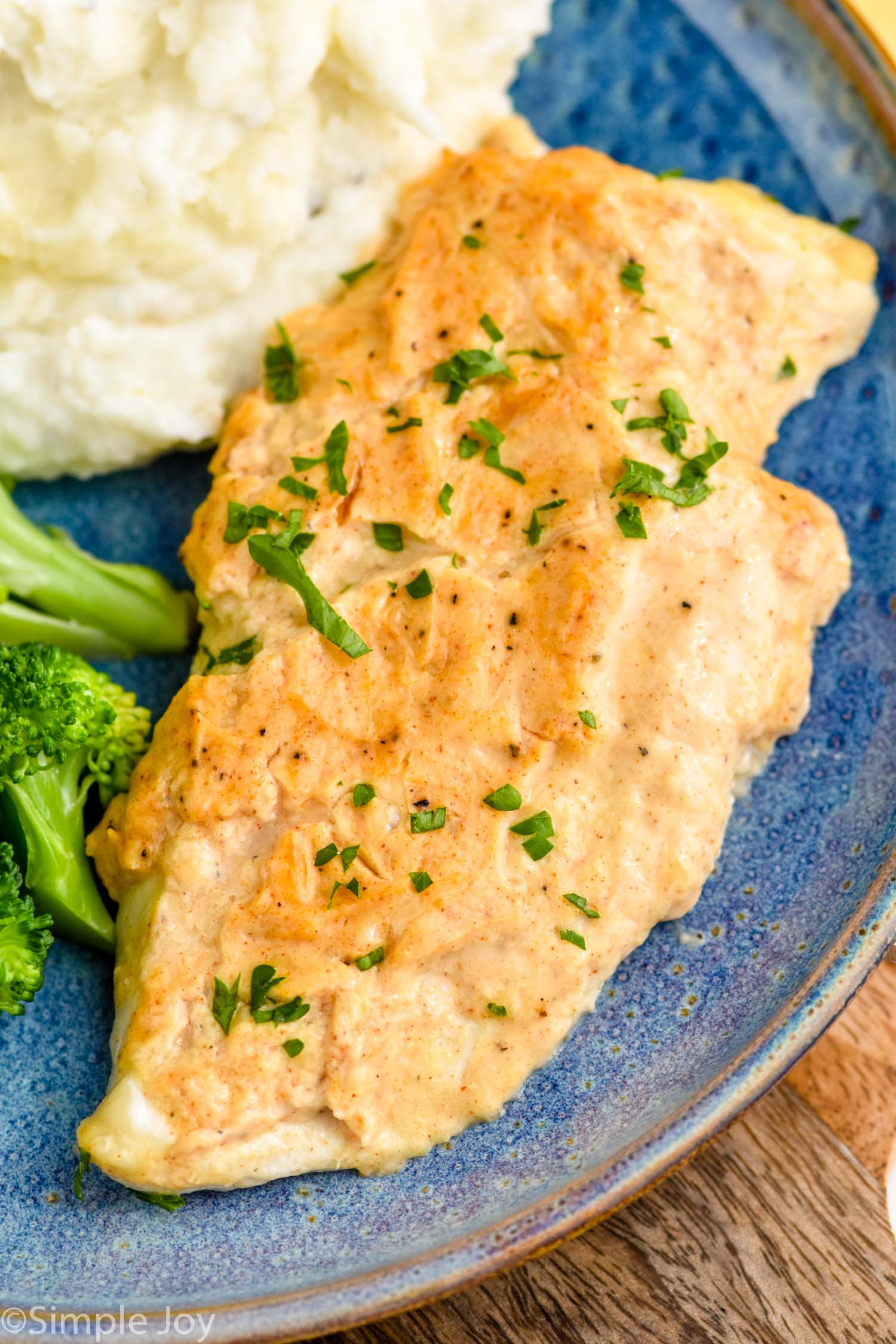 Close up view of Melt In Your Mouth Chicken served on a plate with mashed potatoes and broccoli