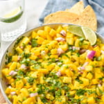 Pinterest graphic for Pineapple Mango Salsa recipe. Text says, "the best Pineapple Mango Salsa simplejoy.com." Image shows a bowl of Pineapple Mango Salsa with chips beside.