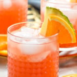 Glasses of rum punch with ice, garnished with orange slice and pineapple wedge