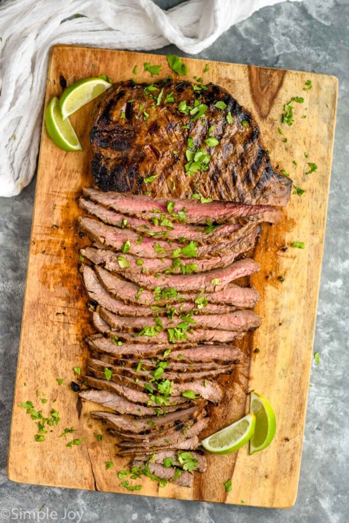 overhead of carne asada meat on cutting board, sliced thin and topped with fresh cilantro 