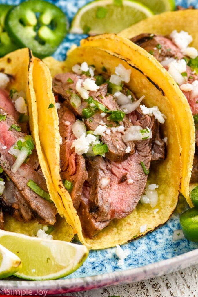 close up of a carne asada taco, topped with jalapeños, onions, cilantro, and cotija cheese