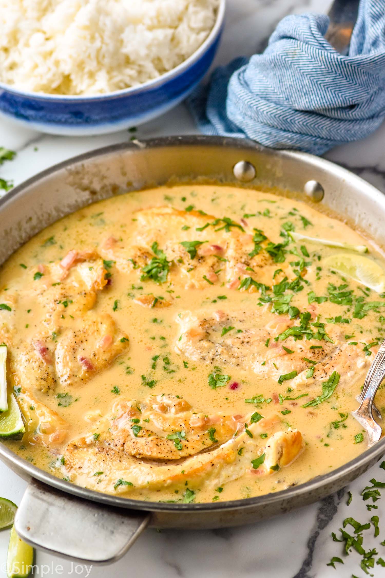 skillet of Coconut Lime Chicken. Bowl of rice sitting in background