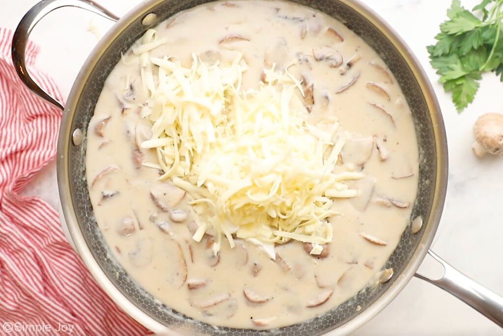 Overhead of skillet of Chicken Tetrazzini ingredients with shredded cheese to make sauce - 7
