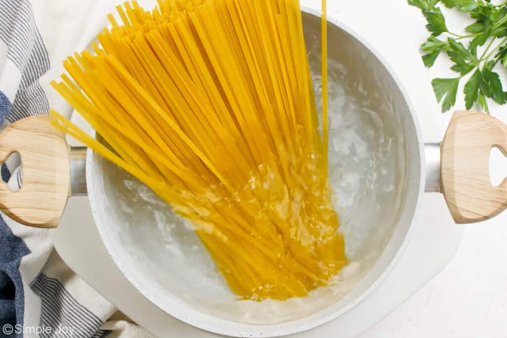 overhead of a pot of boiling water with uncooked fettuccine in it