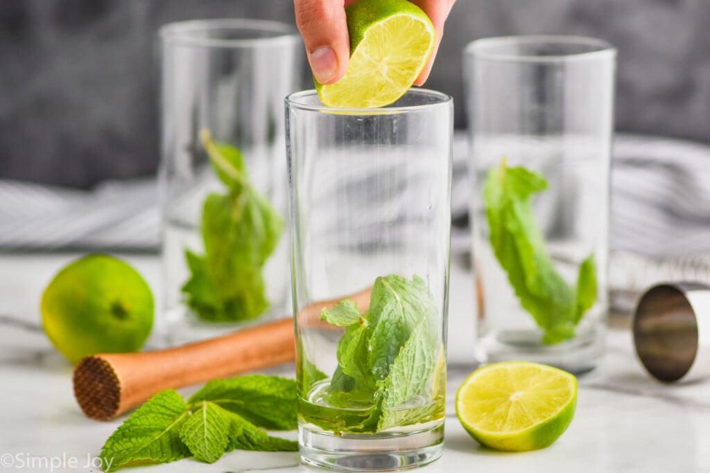 squeezing half of a fresh lime into a high ball glass to make a mojito