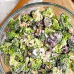 Pinterest graphic for Broccoli Salad recipe. Text says, "the best Broccoli Salad simplejoy.com." Image is overhead view of a bowl of Broccoli Salad with grapes beside.