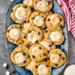Overhead view of a platter of S'mores Cookies. Glasses of milk, graham crackers, marshmallows, and chocolate chips on counter beside. - 19