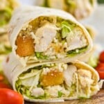 Side view of Chicken Caesar Wrap sliced in half and stacked on top of each other. Tomatoes beside - 11