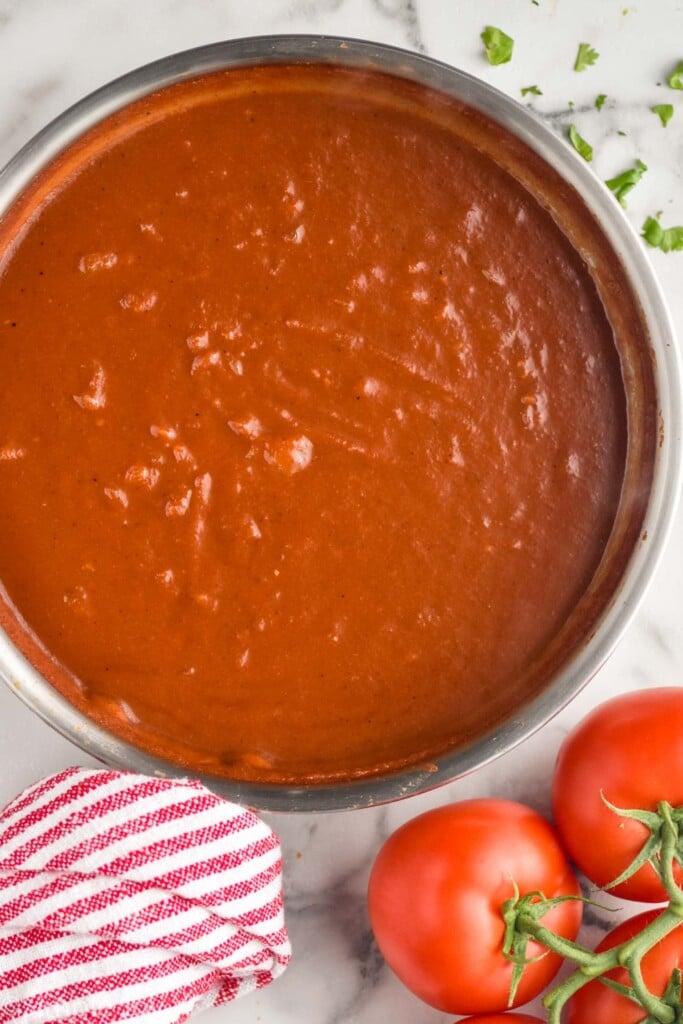 overhead of pot of homemade taco sauce with tomatoes sitting beside