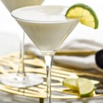 Key Lime Martinis garnished with slices of lime. Additional slices of lime and cocktail jigger beside. - 8