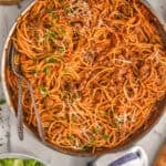 overhead of a skillet with one pot spaghetti with sausage, garnished with parsley and parmesan