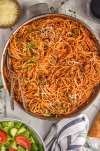 overhead of a skillet with one pot spaghetti with sausage, garnished with parsley and parmesan