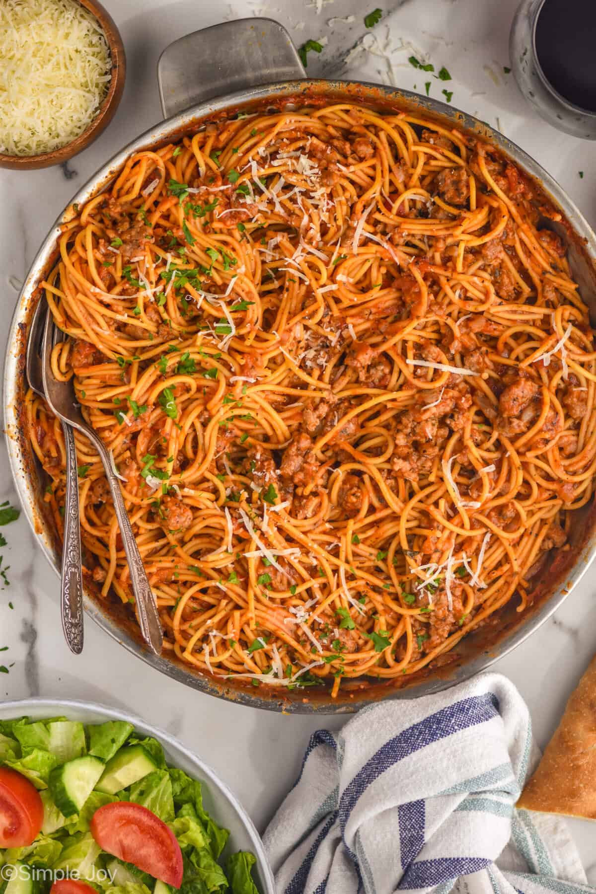 overhead of a skillet with one pot spaghetti with sausage, garnished with parsley and parmesan