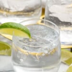 Vodka Tonic garnished with lime wedges. Lime wedges beside. - 8