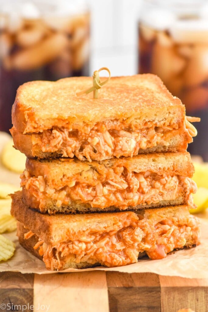 Stack of Buffalo Chicken Sandwich halves with potato chips sitting in background