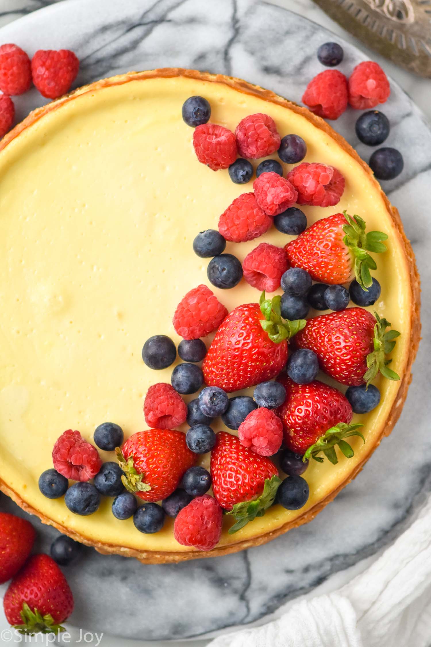 overhead of Easy Cheesecake Recipe topped with fresh strawberries, blueberries, and raspberries