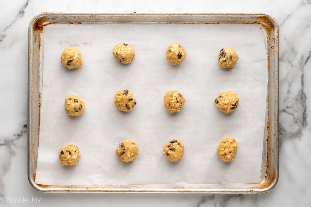 overhead of oatmeal raisin cookies as dough balls before baking on a parchment lined baking sheet