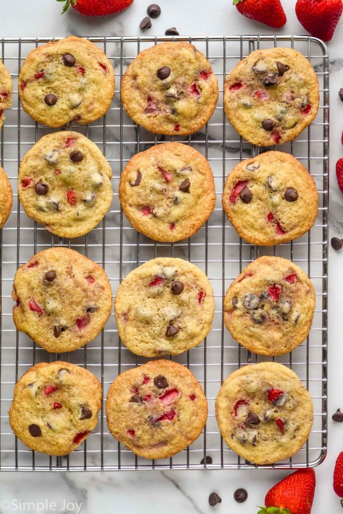 overhead of Strawberry Cookies on a cooling rack with fresh strawberries and chocolate chips sitting beside