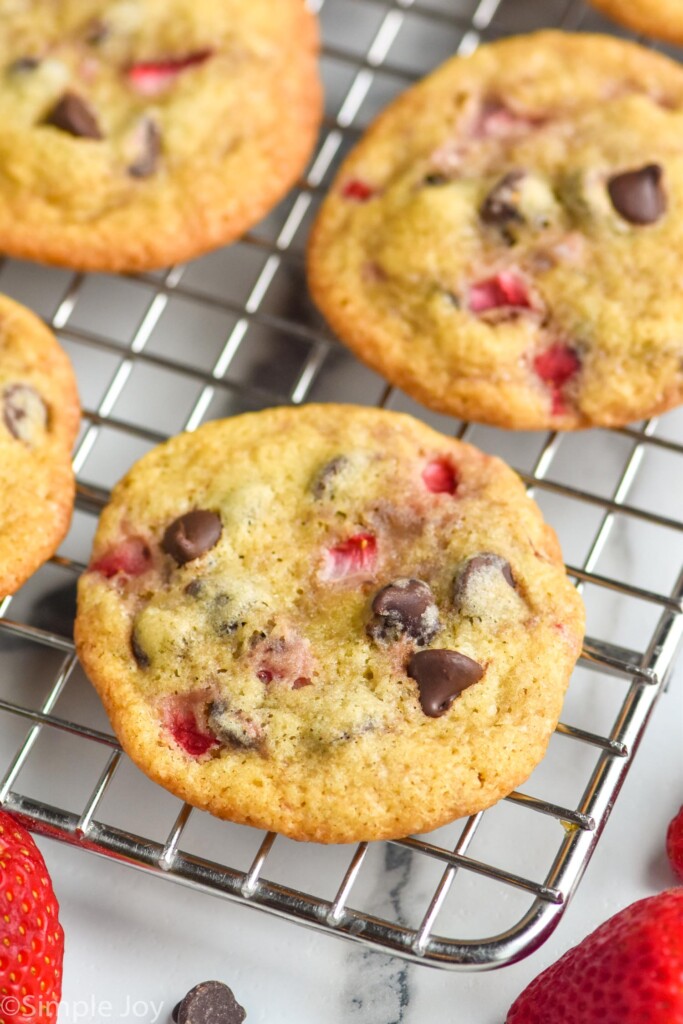 Strawberry Cookies on cooling rack with chocolate chip and fresh strawberries sitting in front.