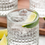 Glass of vodka press with ice and lime wedge. Two glasses of vodka press and lime wedges sitting beside. - 10