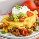 piece of Tamale Pie on a plate topped with sour cream, shredded lettuce, and chopped tomatoes - 10
