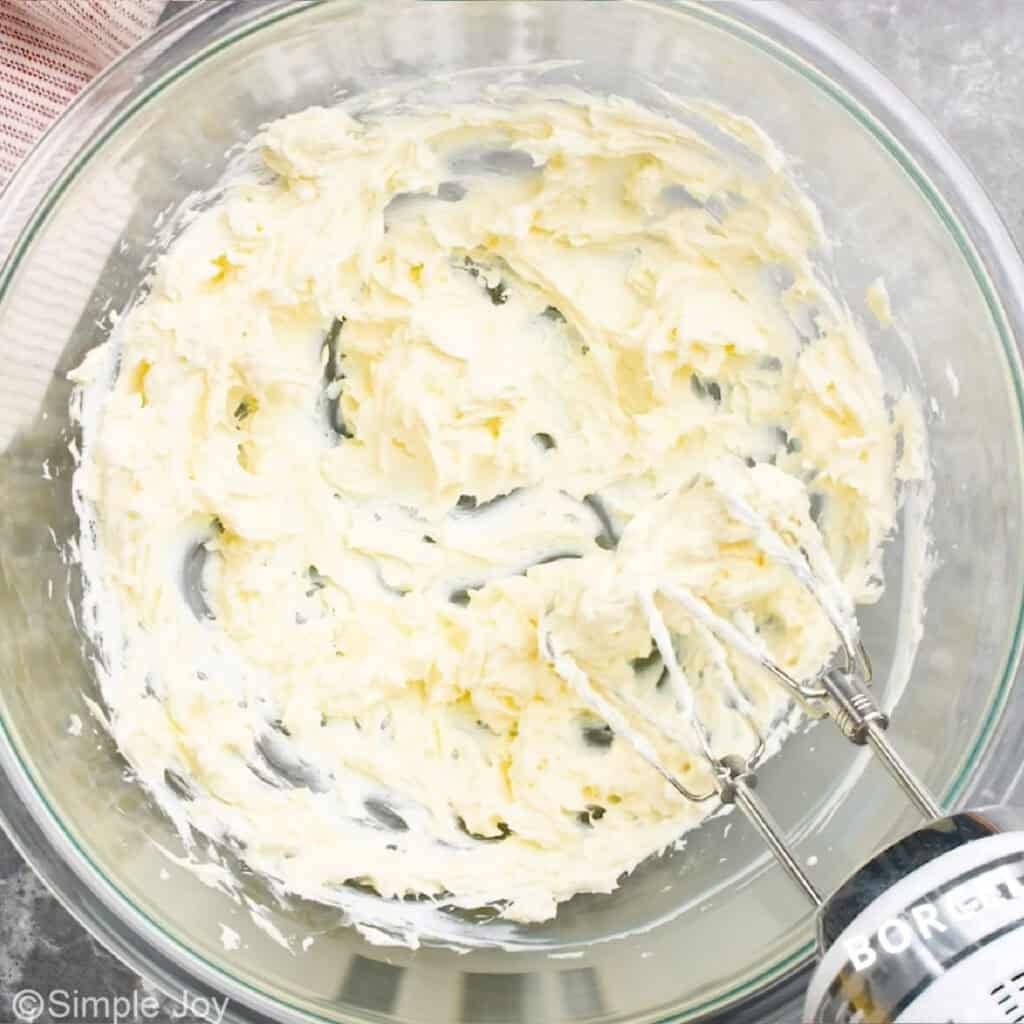 overhead of a bowl with a hand mixer and creamed together cream cheese and butter
