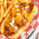 Chili Dogs topped with diced onion with french fries sitting beside - 10