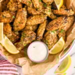 Pinterest graphic for Lemon Pepper Wings. Image shows overhead of basket of Lemon Pepper Wings with lemon wedges and small cup of dipping sauce. Says "super easy Lemon Pepper Wings simplejoy.com"