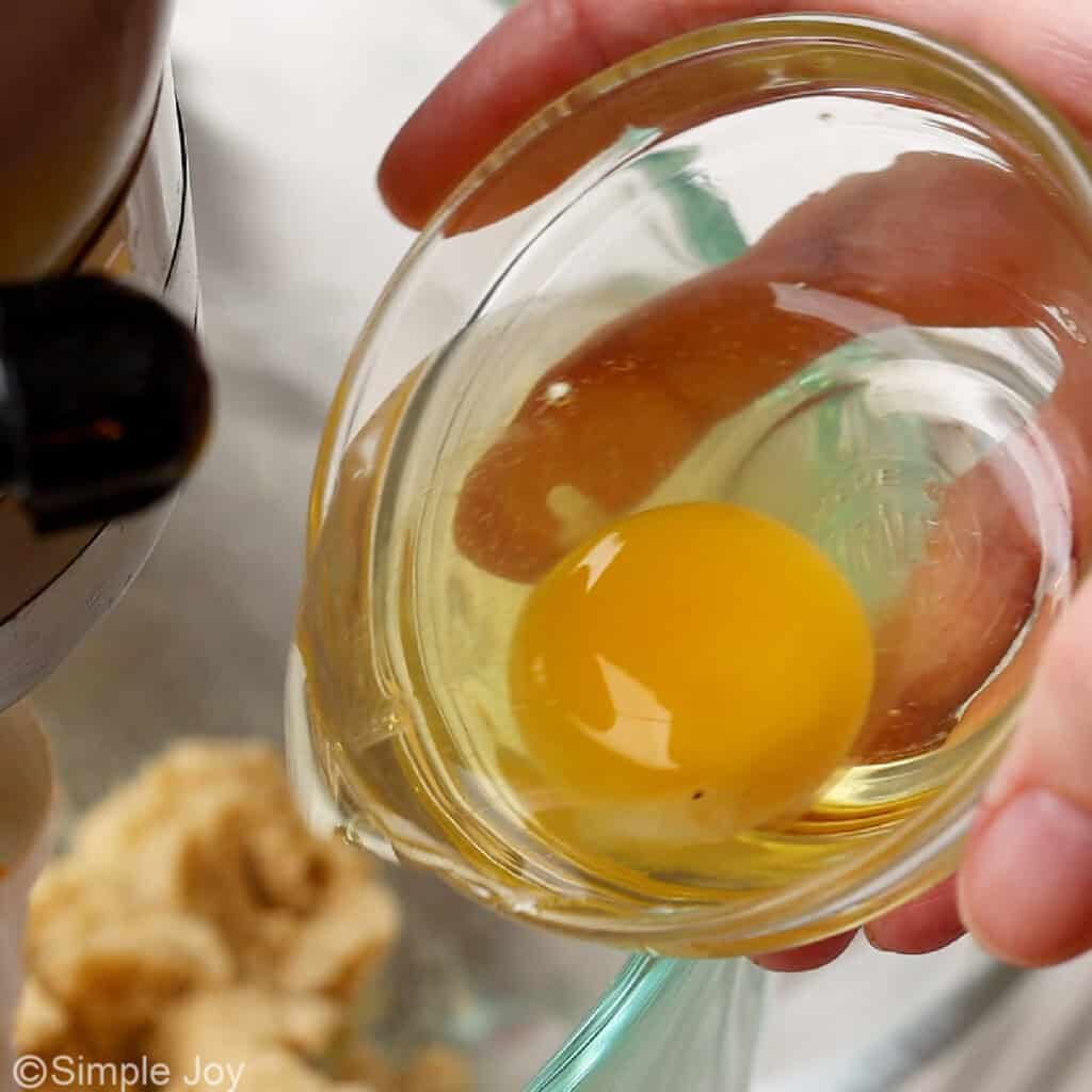 adding an egg to chocolate chip cookie batter