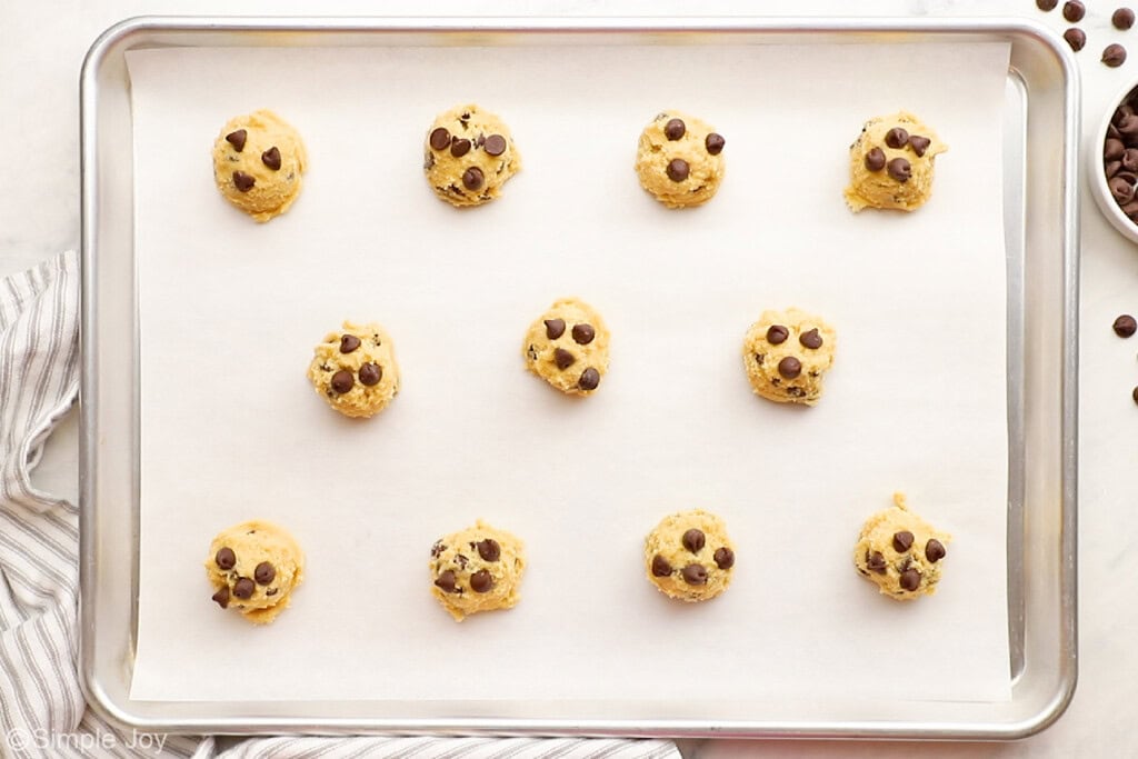 chocolate chip dough balls scooped for baking on a parchment lined baking sheet