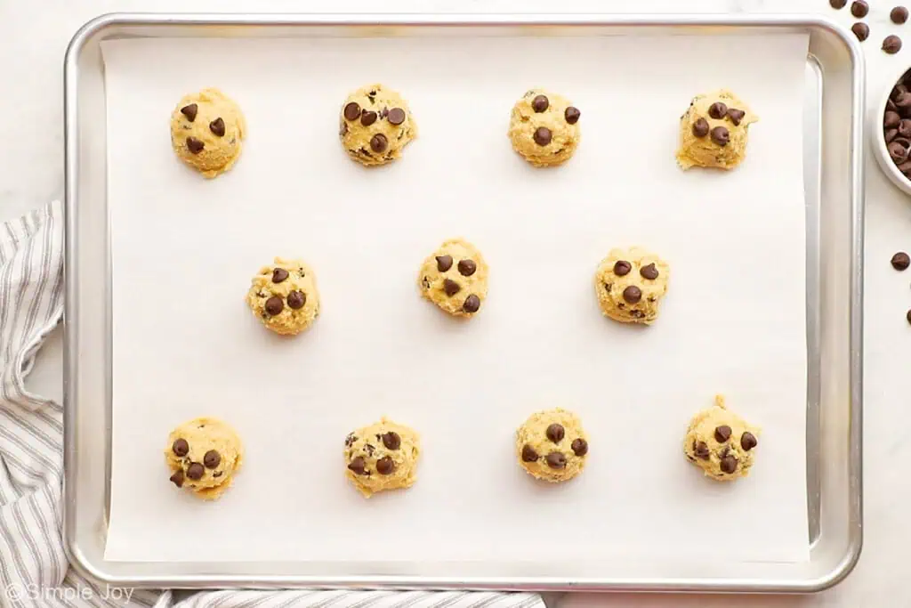 chocolate chip dough balls scooped for baking on a parchment lined baking sheet - 10