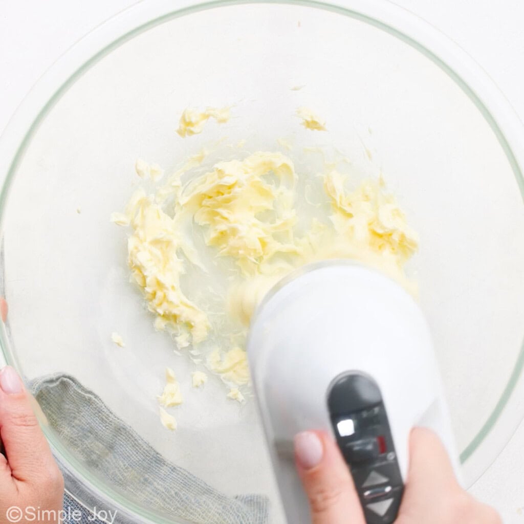 butter being mixed with a hand mixer in a bowl