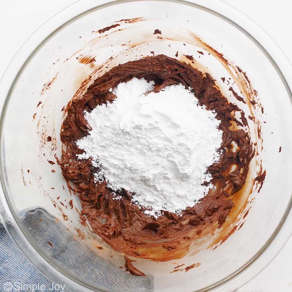 powdered sugar added to a bowl to make chocolate frosting