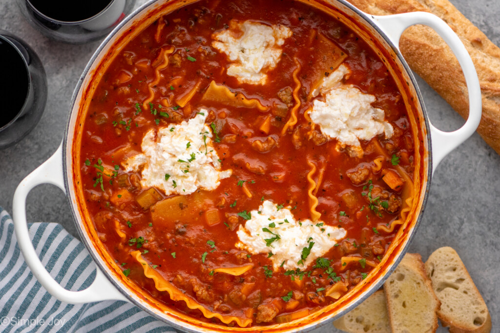 overhead of a stock pot of lasagna soup with drops of ricotta cheese on top