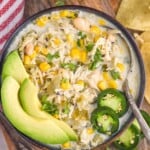 overhead of bowl of Crockpot White Chicken Chili with a spoon topped with avocado slices, jalapeño slices, and fresh cilantro. - 9