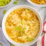 overhead of a bowl of egg drop soup garnished with green onion slices