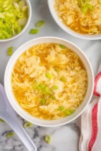 overhead of a bowl of egg drop soup garnished with green onion slices