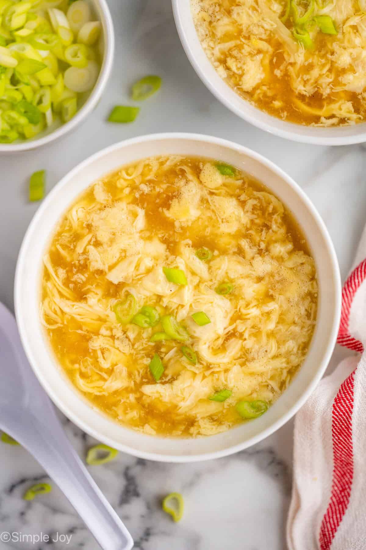 overhead of a bowl of egg drop soup garnished with green onion slices