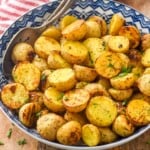 Bowl of Ranch Potatoes topped with fresh parsley with two spoons for serving - 6