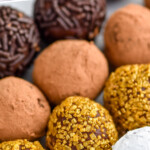 Pinterest graphic for chocolate truffles. Says "the best chocolate truffles simplejoy.com" Image shows close up of chocolate truffles covered in sprinkles, cocoa powder, and powdered sugar.
