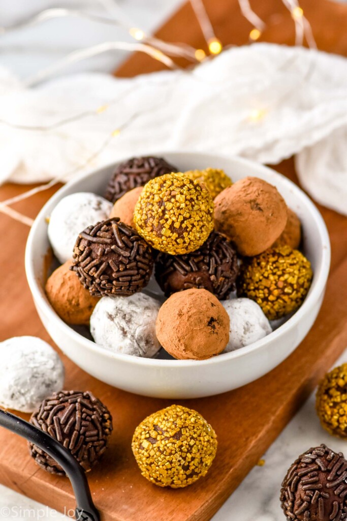 bowl of chocolate truffles covered in sprinkles, cocoa powder, and powdered sugar. Chocolate truffles sitting in front