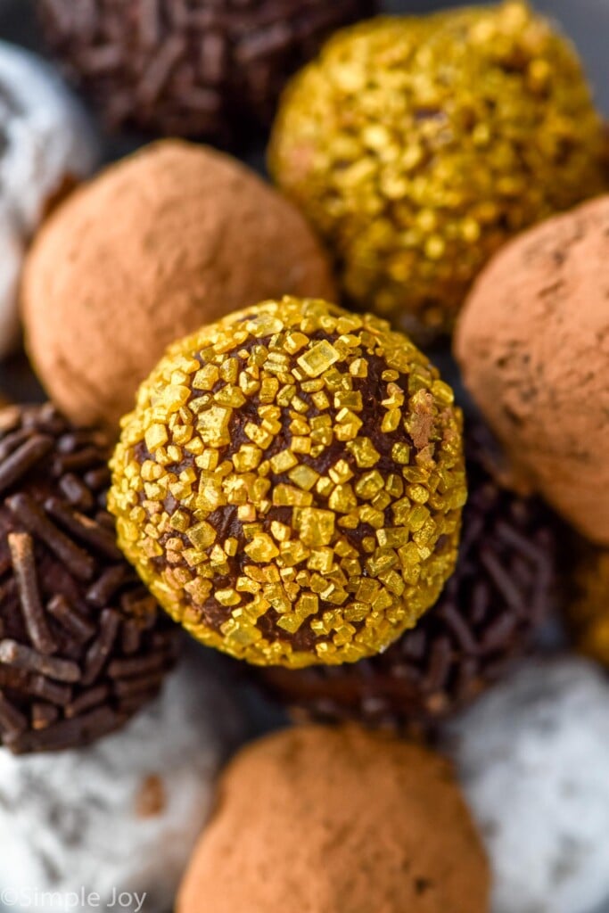 close up of chocolate truffles. Some are covered in sprinkles, powdered sugar, and cocoa powder