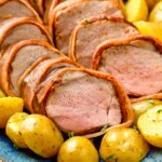 Bacon Wrapped Pork Tenderloin cut and served on a platter with potatoes - 10