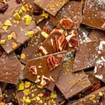 pieces of chocolate bark topped with chopped nuts, dried berries, dried coconut, and salt - 10