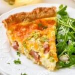 Piece of homemade quiche recipe on a plate with arugula salad - 11