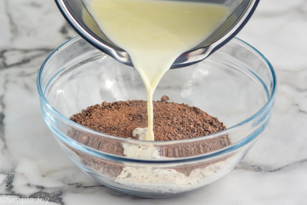 Saucepan of heavy cream pouring into a glass bowl of chopped chocolate to make Chocolate truffles
