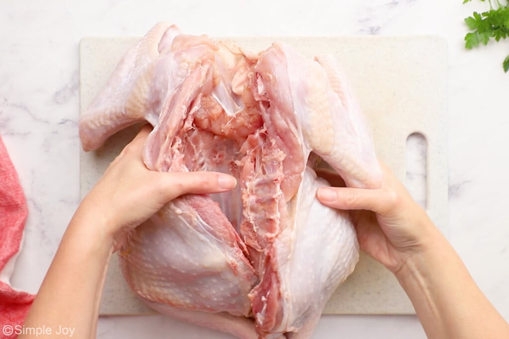 a turkey, breast side down on a cutting board with the backbone missing