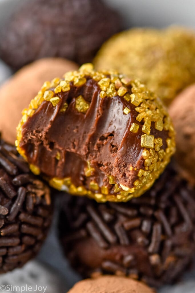 Chocolate Truffles, some covered in sprinkles and some in cocoa powder. Top truffle has bite out of it