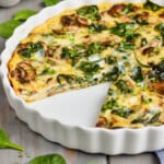 pinterest graphic of a pie plate of crustless spinach quiche recipe missing a piece, says: "crustless spinach quiche simplejoy.com"