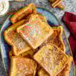Pinterest graphic for Eggnog French Toast. Text says "delicious eggnog french toast simplejoy.com" Image shows overhead of plate of Eggnog French Toast topped with powdered sugar.